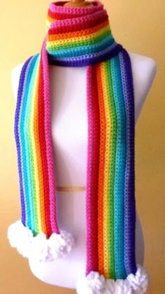 a white mannequin wearing a multicolored knitted scarf with pom - poms