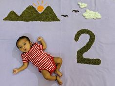 a baby laying on top of a purple blanket next to numbers that spell out 2