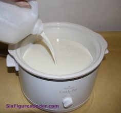 a person pouring milk into an electric crock pot