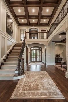 a large foyer with wooden floors and staircases leading up to the second floor, along with an ornate rug on the hardwood floor