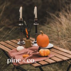 a table with candles, pumpkins and other items on it in front of some tall grass