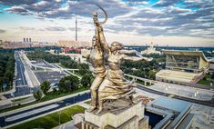 an aerial view of a statue on top of a building in the middle of a city