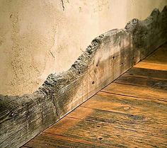 an old wood floor with peeling paint on the wall and wooden planks below it