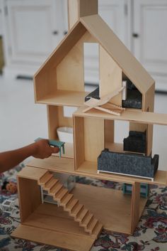 a wooden doll house with stairs and furniture