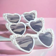 Add a Touch of Glamour to Your Bachelorette Bash with Custom Pearl Heart-Shaped Sunglasses! Make your bridal party unforgettable with our custom, handmade pearl heart-shaped sunglasses. Perfect for your Bachelorette party, Bridesmaids, or even your Honeymoon, these stylish shades are the ultimate accessory to add fun and elegance to your special event. Why You'll Love Them: Personalized Perfection: Choose between Gold or Black Letters and customize the message on each pair to match your celebration. Handcrafted Luxury: Every pair is adorned with pearls, rhinestones, and your custom saying, ensuring a unique and glamorous look for all your photos. Versatile for Any Occasion: Whether it's a Bridal Party, Engagement Party, Bachelorette, or Honeymoon, these sunglasses are the perfect way to sh Bridesmaid Sunglasses, Bridal Sunglasses, Bride Sunglasses, Handmade Sunglasses, Bachelorette Party Bride, Shaped Sunglasses, Heart Shaped Sunglasses, Pearl Heart, Custom Bridal