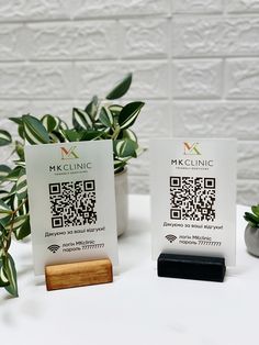 two business cards sitting on top of a table next to a potted green plant