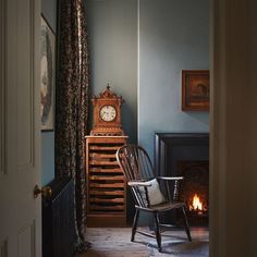 a chair sitting in front of a fireplace with a clock on it