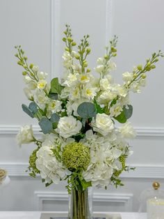 a vase filled with white flowers and greenery