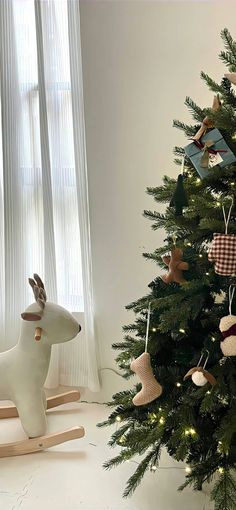 a small christmas tree with ornaments on it and a wooden rocking horse next to it