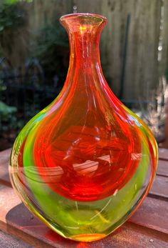 a colorful glass vase sitting on top of a wooden table