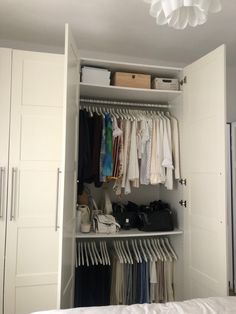 an open closet with clothes, shoes and handbags hanging on the wall next to it