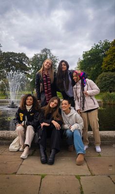 a group of young women sitting next to each other in front of a fountain