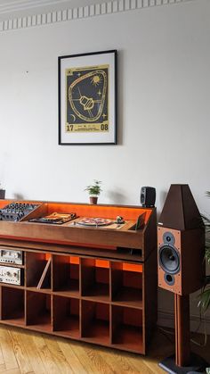 an old record player is sitting on the floor in front of a wall mounted poster