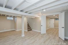 an empty room with wood floors and white pillars in the center is seen from across the room