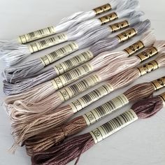 six skeins of thread with gold and silver handles on them, all in different colors