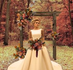 a woman standing in front of a wooden frame with flowers and foliage on it, wearing a wedding dress