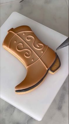 a cookie shaped like a shoe on top of a cutting board next to a knife