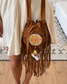 Our Handmade Leather Bag Maya is the perfect sized bag that lights up every outfit. Its classic brown tone and thoroughly finished contrast beading featuring a feather tassel make this piece a real eye-catcher. All leather and adorned with fringes, this statement piece has an adjustable strap to allow you to wear it short or long, across the body or on the shoulder. This beauty will add the perfect finish to any outfit and will see you through a lifetime of seasons. Wear it with a knotted tee, y Hippie Handmade Brown Shoulder Bag, Hippie Brown Handmade Shoulder Bag, Bohemian Bags As Festival Gift, Bohemian Bags For Festival Gift, Handmade Festival Pouch Bags, Bohemian Brown Hand-stitched Bags, Bohemian Festival Gift Bags, Handmade Leather Festival Bag, Brown Shoulder Bag For Travel And Festivals