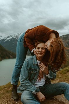 a man and woman sitting on the ground with mountains in the backgroung