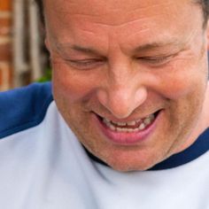 a close up of a man smiling and holding a piece of pizza in his hand