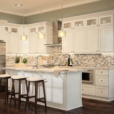 a large kitchen with white cabinets and counter tops, two stools in front of the island