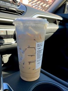 a cup of iced coffee sitting on top of a car dashboard