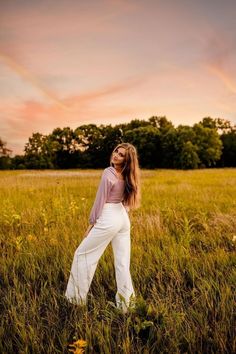 a woman standing in the middle of a field with her hands on her hips and looking off into the distance