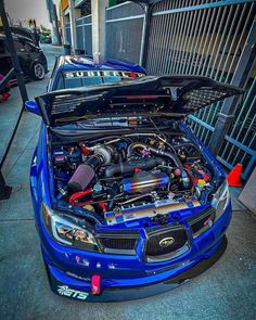 a blue car with its hood open and engine in the trunk