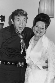 an old black and white photo of a man and woman posing for the camera with their arms around each other