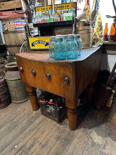 an old wooden table with two jars on it and other items in the back ground