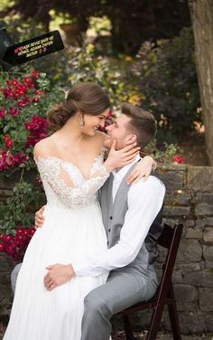 a bride and groom sitting on a bench in front of some flowers at their wedding