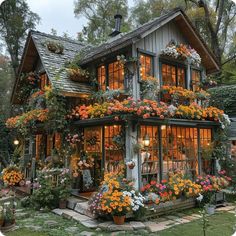 a house with flowers on the windows and plants growing all over it's sides