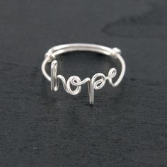 a silver ring with the word hope written in cursive writing on it's side