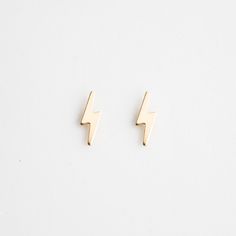 pair of gold earrings with lightning bolt design on them, against a plain white background