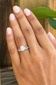 a woman's hand with a diamond ring on her finger and a plant in the background