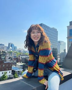 a woman sitting on top of a roof with buildings in the background