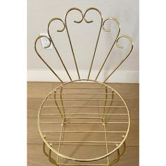 a gold metal rack with four pairs of scissors in it on a wooden floor next to a white wall