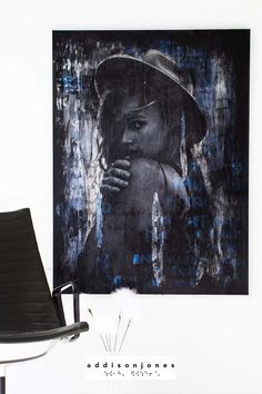 a black chair sitting next to a painting on the wall