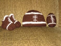 a crocheted football hat, mitt and booties are sitting on a couch