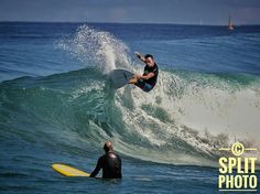 a man riding a surfboard on top of a wave in the ocean next to another person