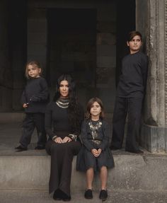 three children and one adult sitting on steps