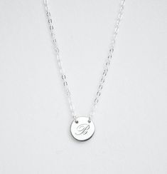 INITIAL NECKLACEThis beautiful minimalist initial or letter pendant necklace is perfect for everyday wear. It would make the perfect gift for a friend, mom, bridesmaid, or any loved one! The small round disk is held in place on the chainIf you want a layered look, click here to view the second necklace shown on our model - our 16mm size.DESCRIPTION• Material: High quality solid 925 sterling silver• Dimensions: 9mm disc• Finish: Sterling Silver ∙ 18K Gold ∙ Rose Gold• All our jewelry is custom an Minimalist Monogram Initial Necklace In White Gold, Minimalist White Gold Monogram Initial Necklace, Minimalist White Jewelry With Monogram, Delicate Silver Initial Pendant Name Necklace, Delicate Silver Initial Pendant Necklace, Minimalist White Initial Necklace For Personalized Gift, Minimalist Everyday Round Initial Necklace, Silver Minimalist Initial Necklace With Delicate Chain, Elegant Hypoallergenic Charm Necklace With Initial Pendant