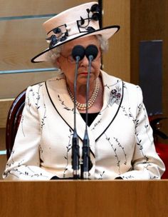 an older woman wearing a white hat and holding a microphone