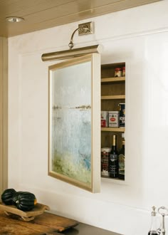 a painting hanging on the wall above a kitchen counter next to a wooden cutting board