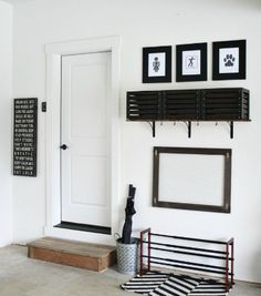 a white room with black and white artwork on the wall, framed pictures above it