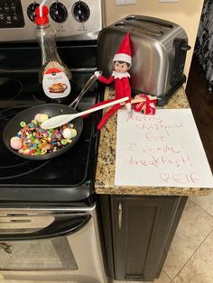 an elf is sitting on the kitchen counter next to his toaster oven and sign