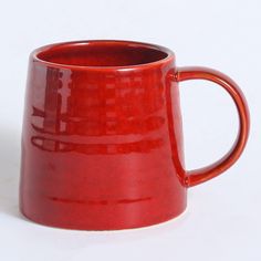 a red coffee mug sitting on top of a white table