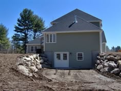 a gray house sitting on top of a dirt field