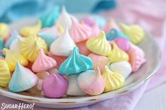 there is a plate full of small colorful candies on the table with pink and blue napkins