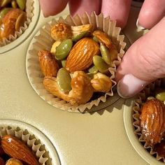 someone is picking up some nuts from the muffin tins